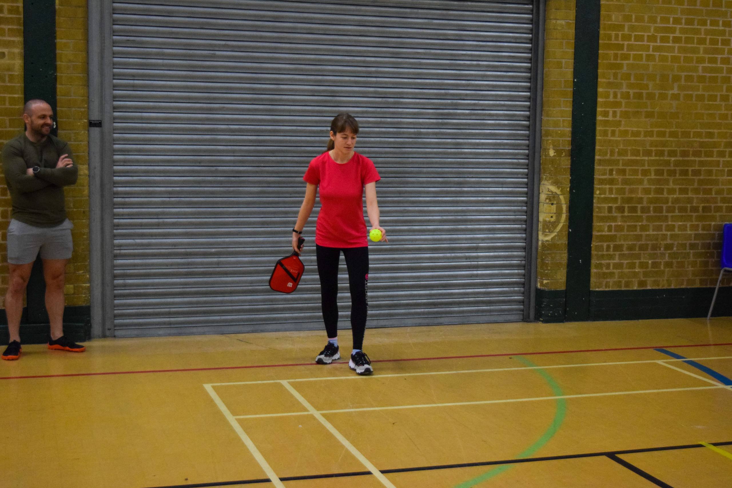 a woman holding a pickleball racket and a ball