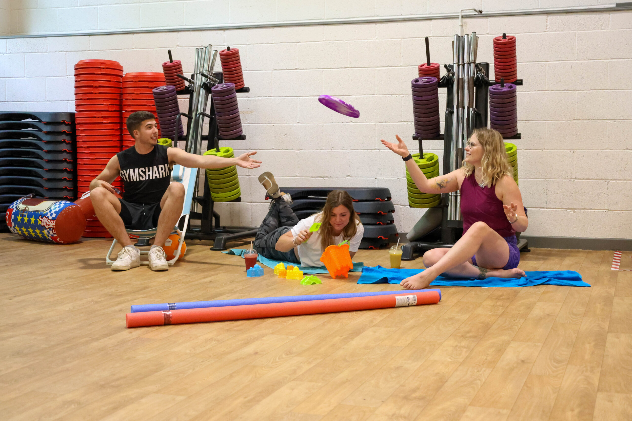 a group of people sitting on the floor of a gym pretending it is the beach