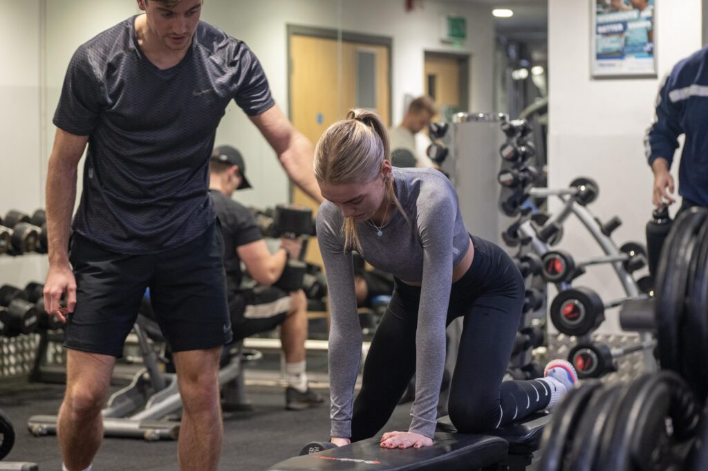 a woman in a gym with a PT - Personal Training Jobs at Horizon