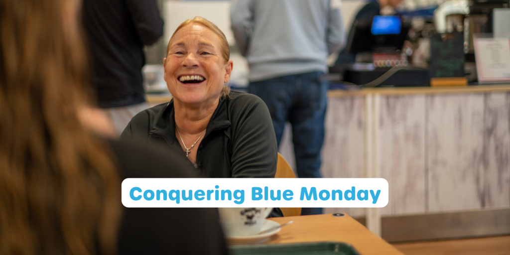 a woman laughing at a table at Horizon cafe for the cover of a Conquering Blue Monday blog post