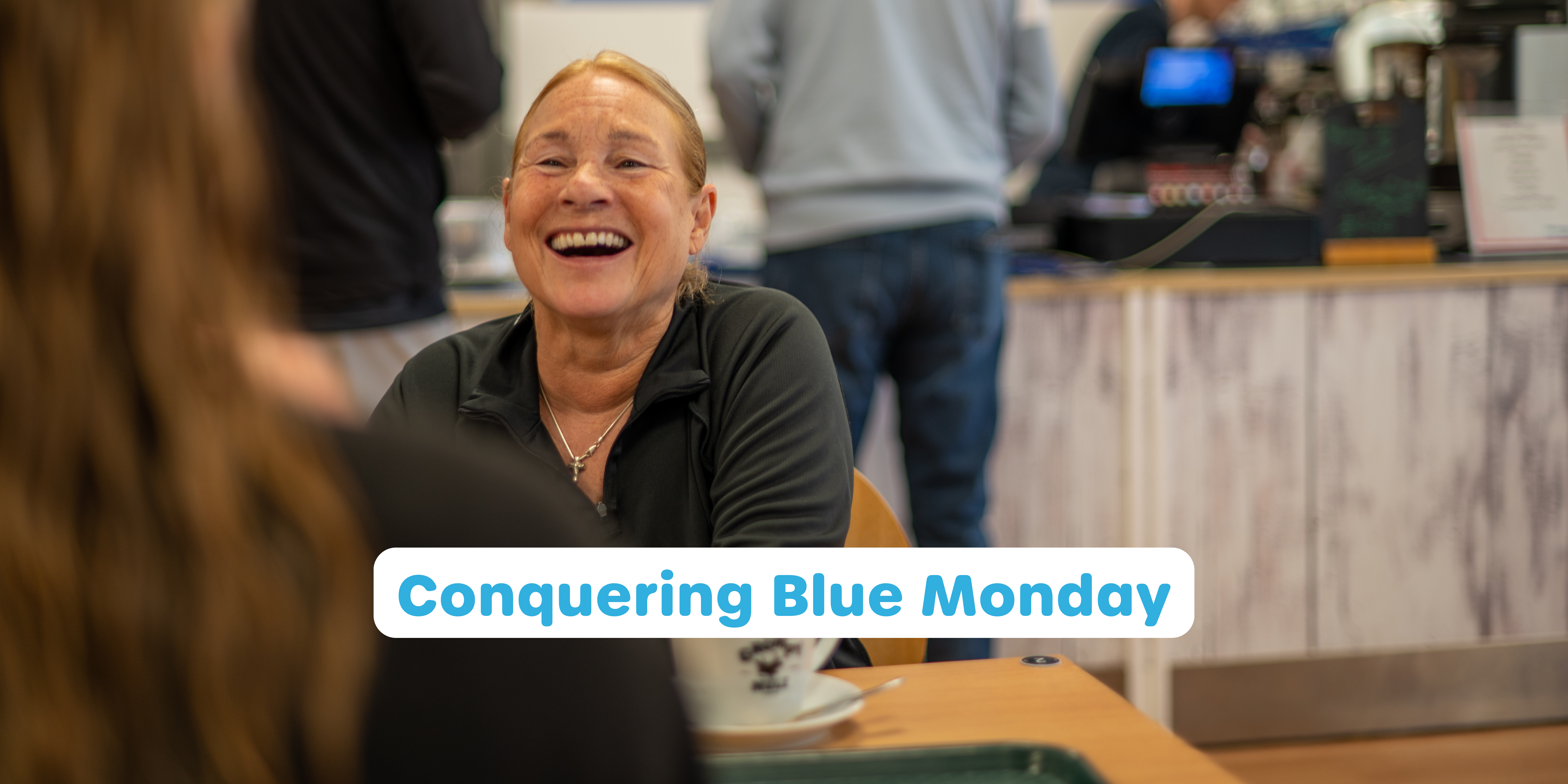 a woman laughing at a table at Horizon cafe for the cover of a Conquering Blue Monday blog post