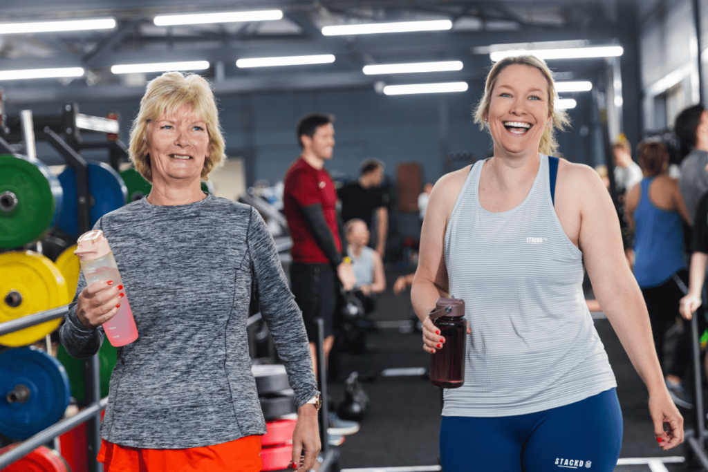 Two ladies looking happy taking part in a HYROX class