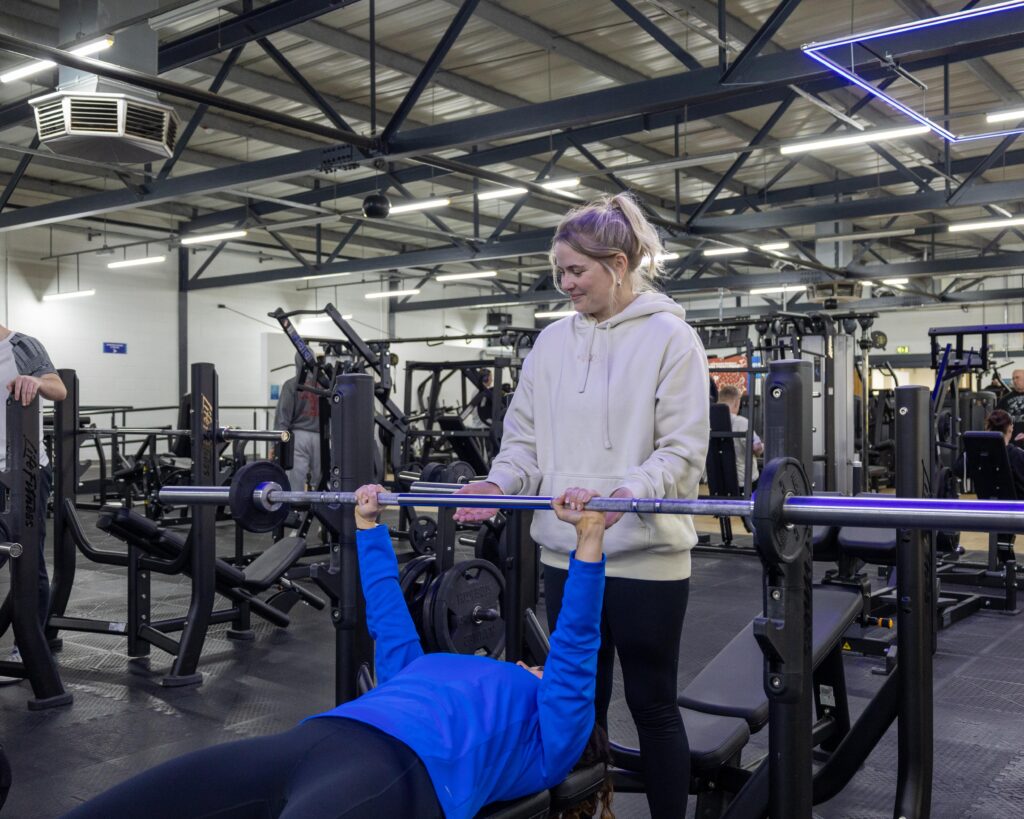 Person lifting weights with assistance