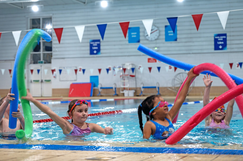 Children enjoying swimming with pool noodles.