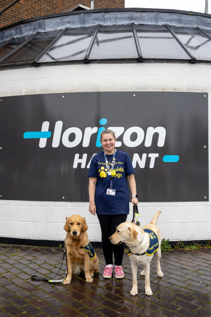 Woman with two guide dogs outside building.